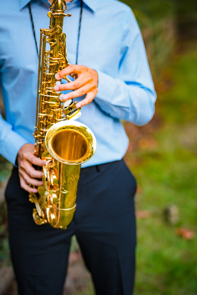 Closeup of a high school senior playing his saxophone in a park in Redmond, WA photographed by Maë Lans Photography of https://eastsidefamilyphotographer.com