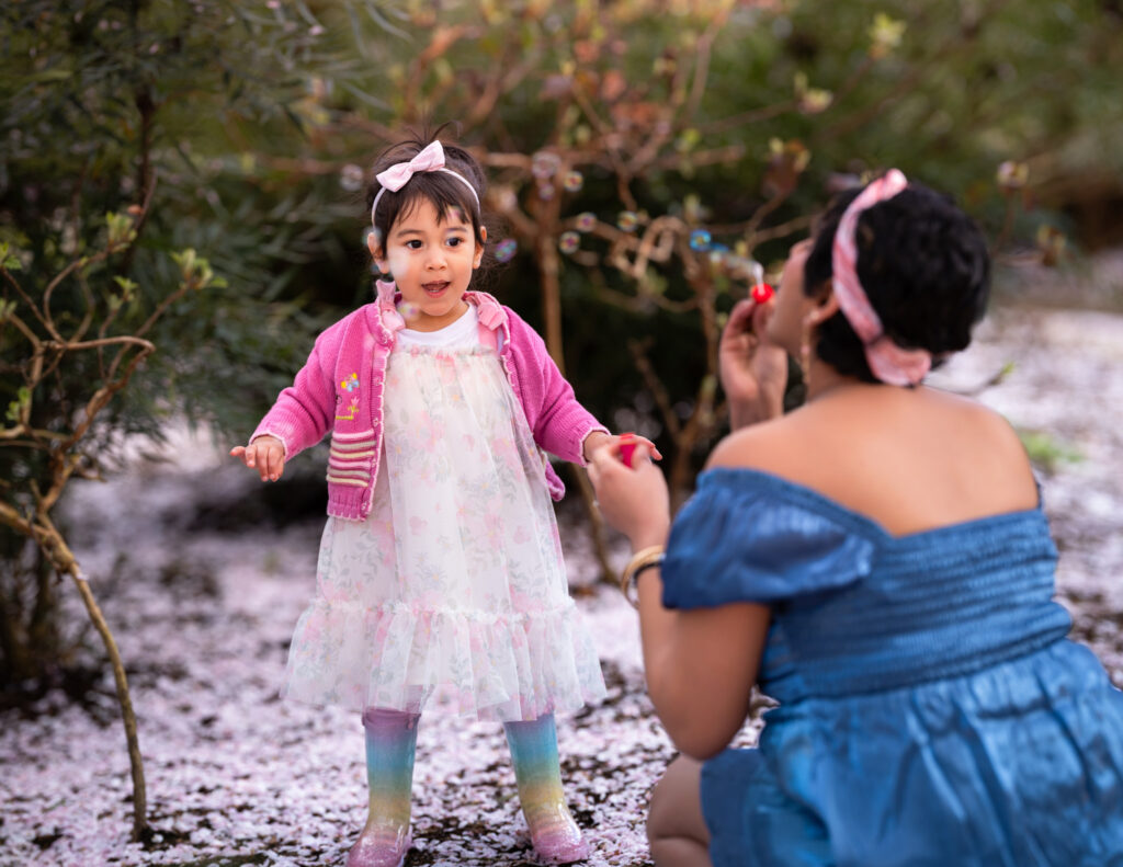 Mother and daughter enjoying blowing bubbles at the Bellevue Downtown Park during their cherry blossom family photoshoot.