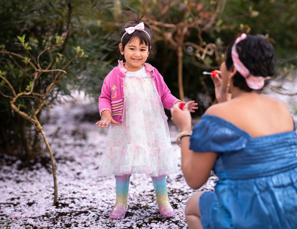 Daughter showing delight at the bubbles her mom is blowing in the Bellevue Downtown Park during their cherry blossom family session.